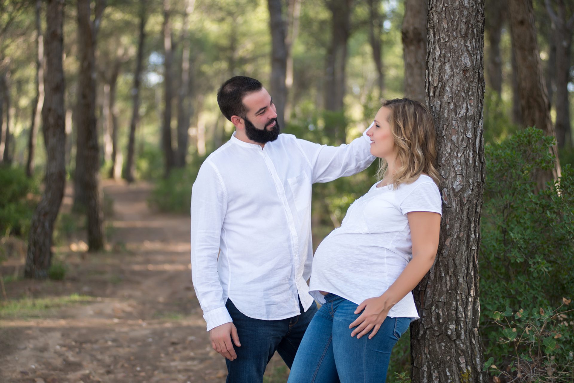 Fotografía de embarazada con su pareja en el bosque mirándose