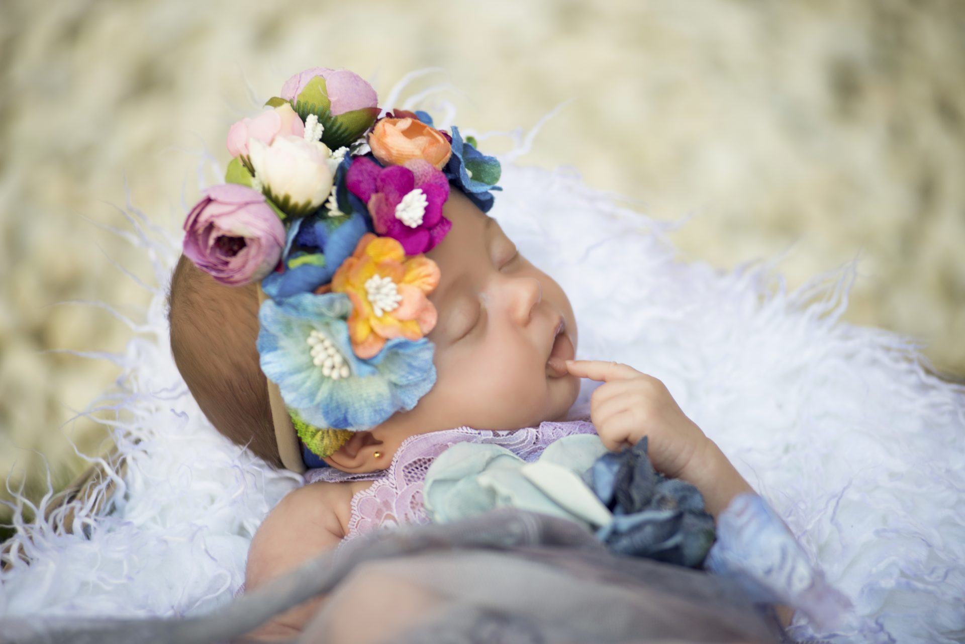 Fotografía de bebe recien nacida con corona de flores en el campo