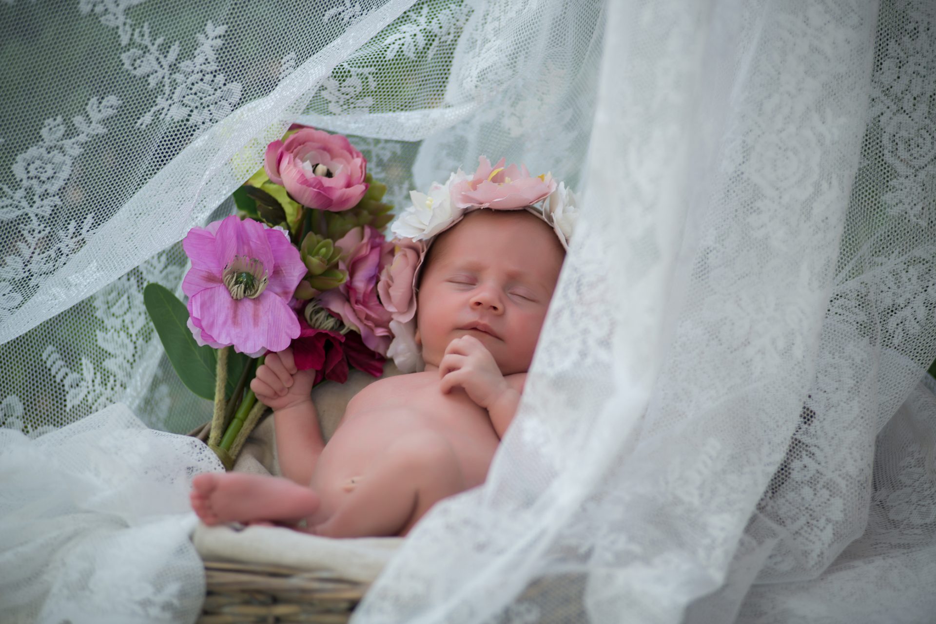 Fotografía de bebe en el campo con corona y ramo de flores